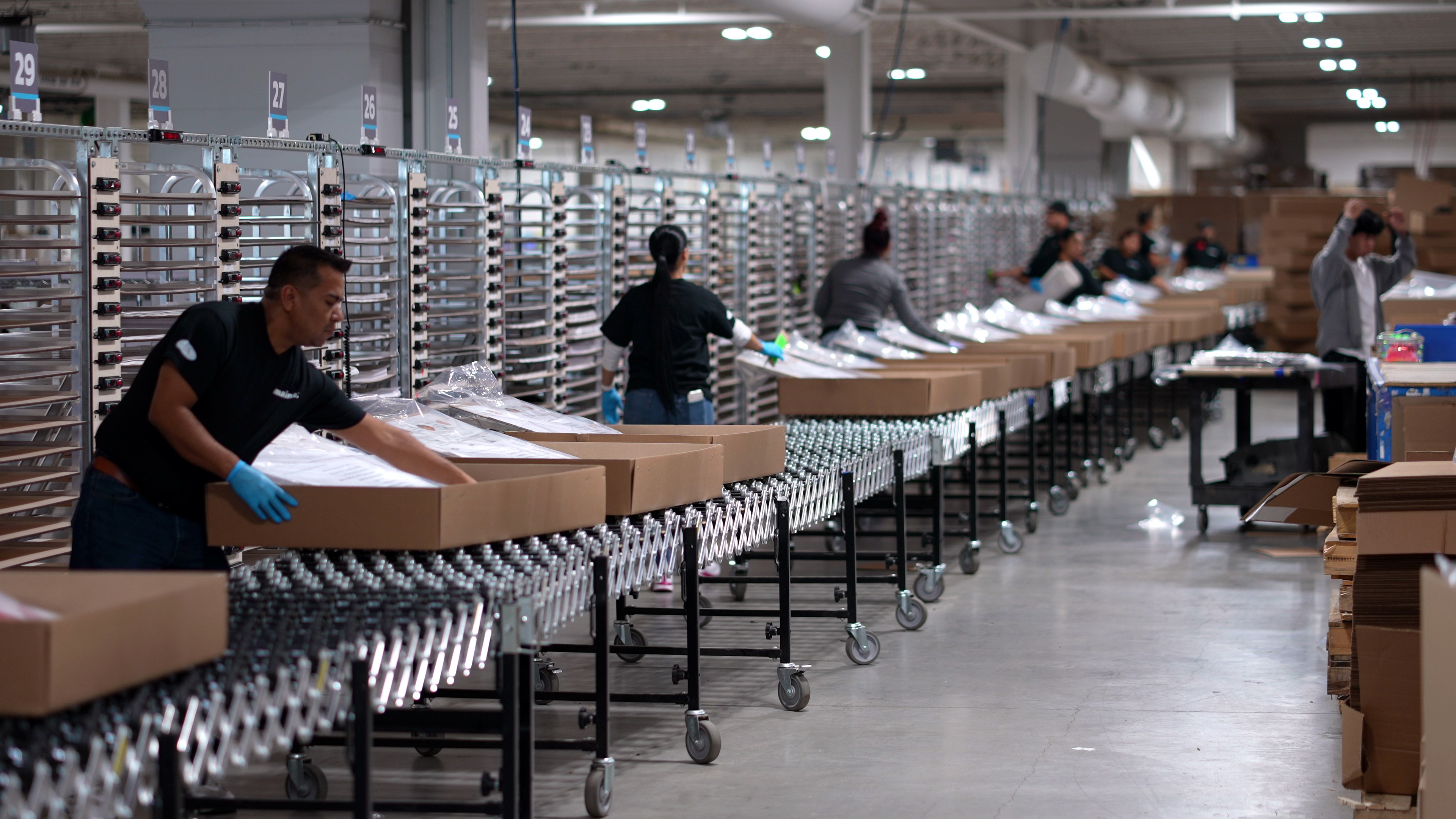 Imagine production team kitting and packing boxes along a warehouse conveyor line